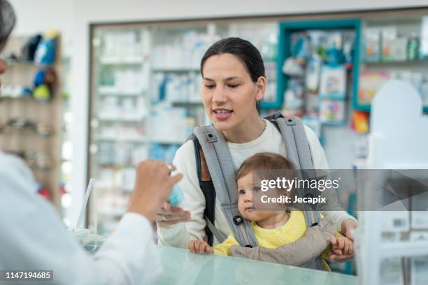 moeder met een kind testen handcrème - pharmacy stockfoto's en -beelden