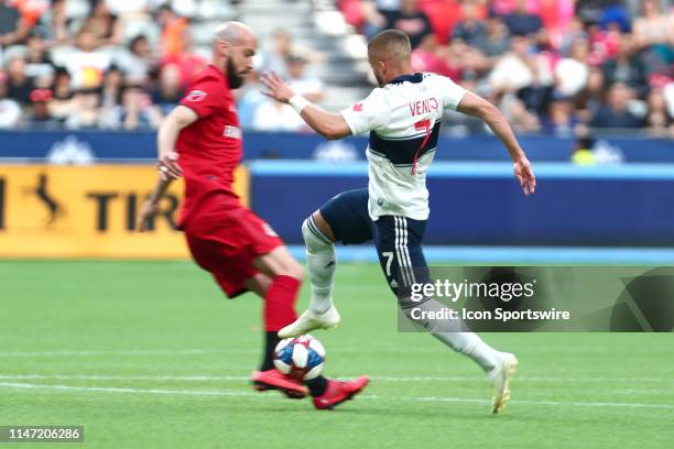 Vancouver Whitecaps midfielder Lucas Venuto runs the ball by Toronto FC defender Laurent Ciman during their match at BC Place on May 31, 2019 in...