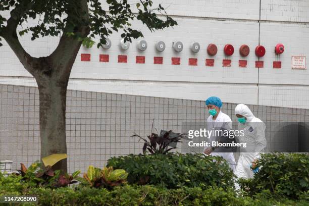 Workers wearing face masks and dressed in gowns walk inside the Sheung Shui Slaughterhouse facility in Hong Kong, China, on Saturday, June 1, 2019....
