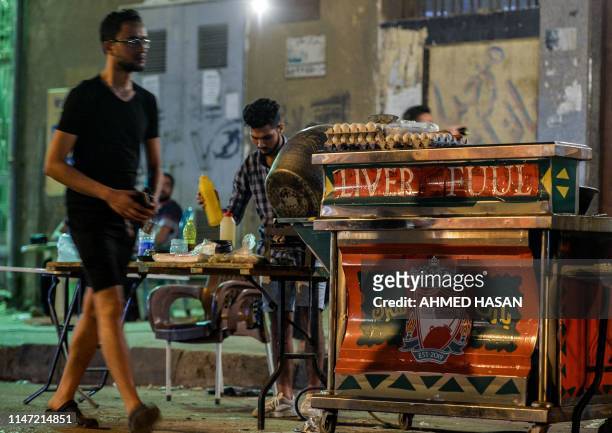 An Egyptian man cooks food during the pre-dawn 'suhur' meal before a new day of fasting begins, early on May 31 near a food cart by the name "Liver...