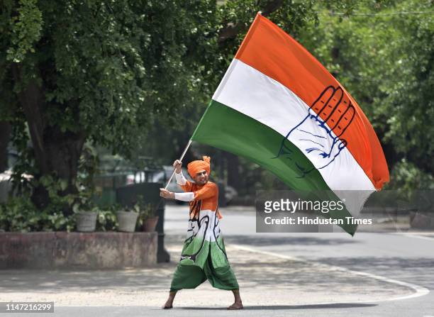 Congress worker waves party flag during a protest outside Rahul Gandhis residence urging him to continue as Congress President, at Tughlaq Lane, on...