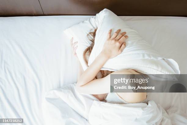 high angle view of young woman lying on bed and she hate to waking up in the early morning. - insomnia stockfoto's en -beelden