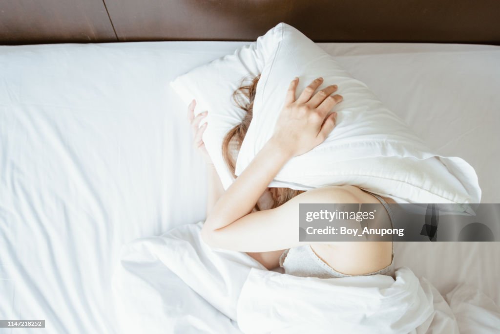 High angle view of young woman lying on bed and she hate to waking up in the early morning.