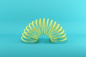 Yellow slinky isolated on blue background. Minimal conceptual idea concept.