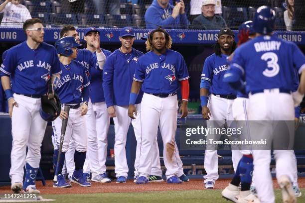 Brandon Drury of the Toronto Blue Jays is congratulated by Danny Jansen and Luke Maile and Aaron Sanchez and Clay Buchholz and Vladimir Guerrero Jr....