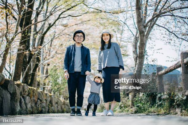 portrait of a loving family of three holding hands and enjoying intimate family time together on a lovely sunny day in the nature - 日常の一コマ ストックフォトと画像