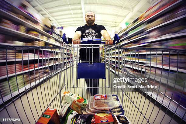 man pushing shopping trolly - scott macbride stock pictures, royalty-free photos & images