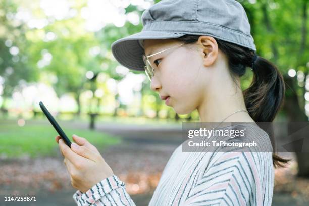 girl reading an ebook at a public park - otaku stock pictures, royalty-free photos & images