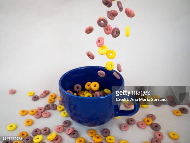 lots of colorful cereal loops falling into a bowl for breakfast - cheerios stock-fotos und bilder