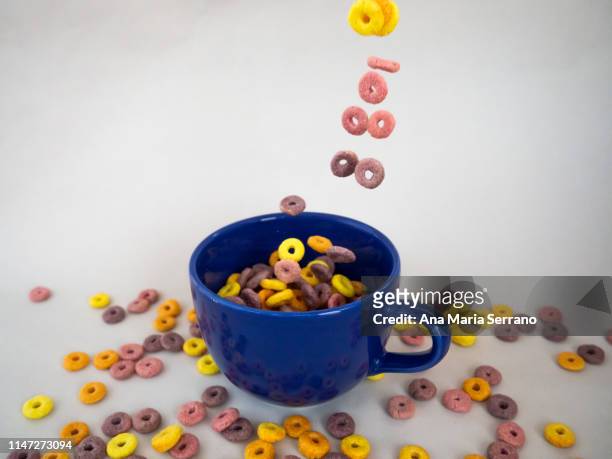 lots of colorful cereal loops falling into a bowl for breakfast - cheerios stock-fotos und bilder
