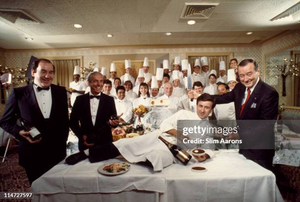 Italian-born restaurateur Sirio Maccioni with staff at Le Cirque, his establishment in New York, 1990. Maccioni is holding a large carving knife over...