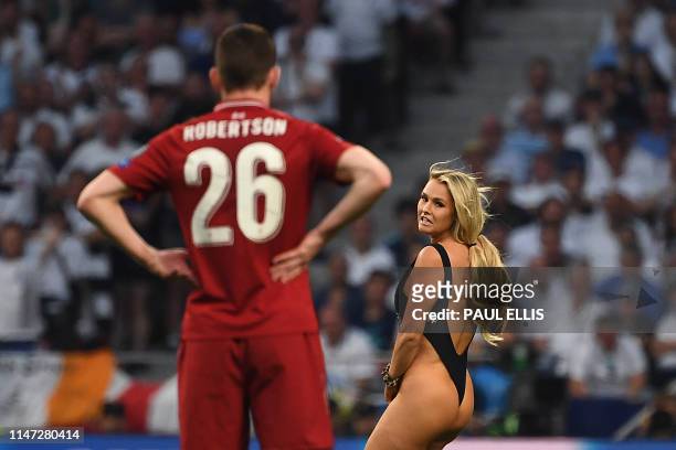 Liverpool's Scottish defender Andrew Robertson looks at a pitch-invader running on the pitch during the UEFA Champions League final football match...