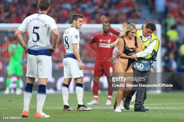 Harry Winks of Spurs looks on as a female streaker is escorted off the pitch by a steward during the UEFA Champions League Final between Tottenham...