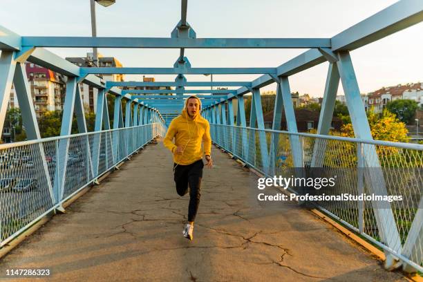 jonge sportsman die op de brug loopt - man running city stockfoto's en -beelden