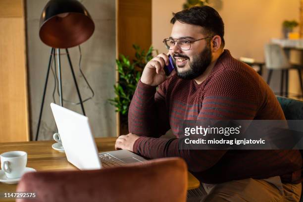 overweight businessman making a phone call in cafeteria - fat people stock pictures, royalty-free photos & images