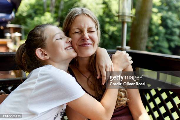 happy girl hugging mother on terrace - mama kind kuscheln stock-fotos und bilder