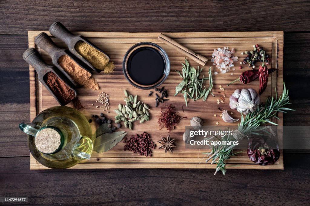 Verscheidenheid van piment ingrediënten en specerijen voor voedsel kruiden op snijplank in ouderwetse keuken