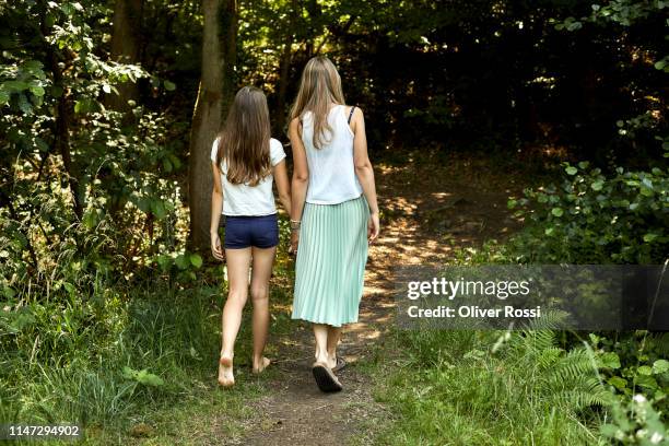 rear view of mother and daughter walking hand in hand on a forest path - girls with short skirts photos et images de collection