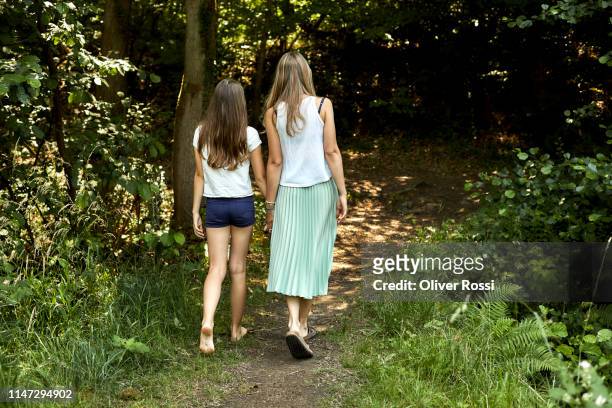 rear view of mother and daughter walking hand in hand on a forest path - 13 year old girls in shorts stock pictures, royalty-free photos & images