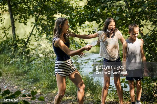 carefree mother and kids splashing with water bottle in summer - 11 loch stock pictures, royalty-free photos & images