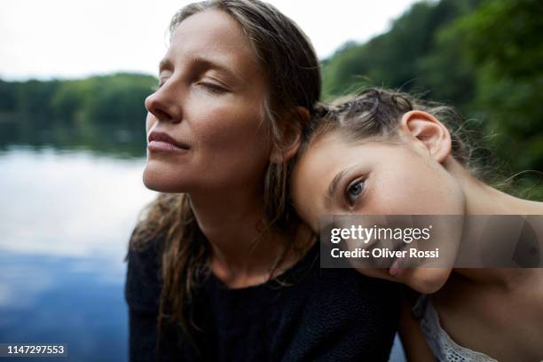 portrait of affectionate mother and daughter at a lake - woman portrait eyes closed stock-fotos und bilder