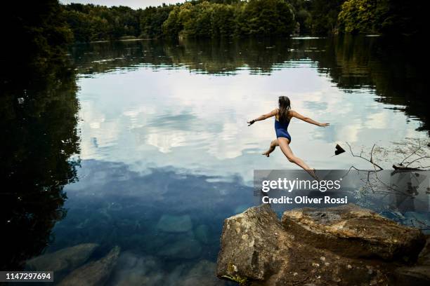 rear view of girl jumping into a lake - den sprung wagen stock-fotos und bilder