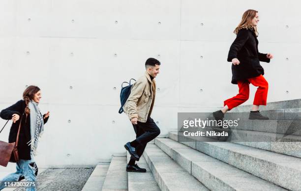 friends running up steps in urban setting - staircase stock pictures, royalty-free photos & images