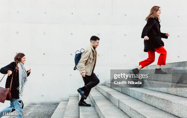 friends running up steps in urban setting - staircase imagens e fotografias de stock