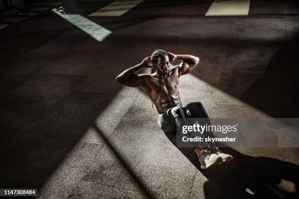 above view of sweaty black athlete doing sit-ups in a gym. - bodyweight training stock pictures, royalty-free photos & images