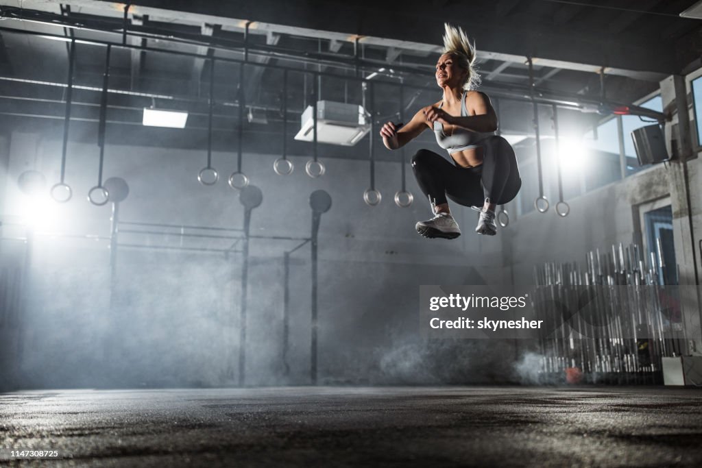 Below view of athletic woman exercising jumps in a gym.