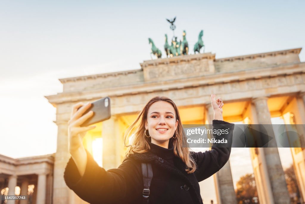 Young woman taking selfie at Brandeburg Gate in Berlin