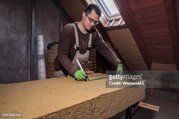 roof insulation, worker measuring wood fibre insulation - house insulation not posing stock pictures, royalty-free photos & images