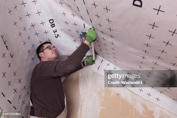 roof insulation, worker fixing sarking membrane - house insulation not posing stock pictures, royalty-free photos & images