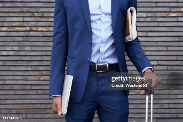 businessman with newspaper, laptop and trolley bag wearing blue suit, partial view - england media access stock pictures, royalty-free photos & images