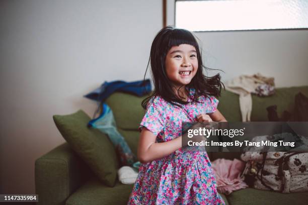 lovely little girl getting dressed joyfully by herself at home in the morning - mädchen kleid stock-fotos und bilder