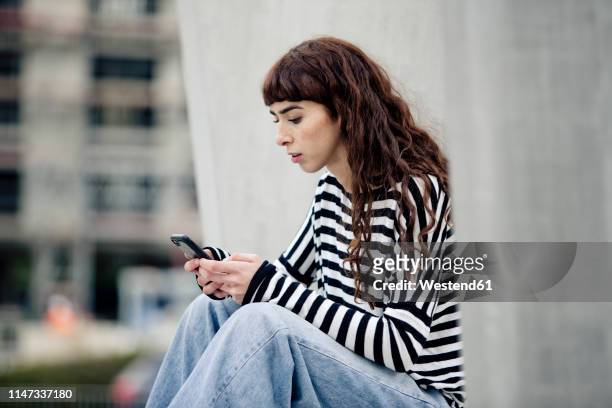 young woman wearing striped shirt, using smartphone - essen ruhrgebiet stock-fotos und bilder
