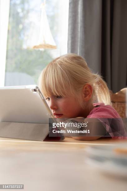 portrait of blond little girl using digital tablet at home - myopia 個照片及圖片檔