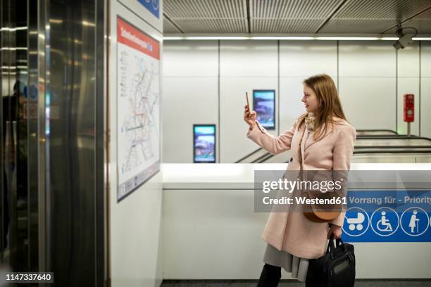 austria, vienna, young woman taking photo of map at underground station - go single word stock pictures, royalty-free photos & images