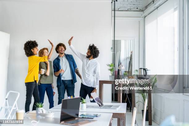 young entrepreneurs having a meeting in their office - business people cheering stock-fotos und bilder