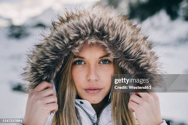 portrait of young blond woman wearing hood in winter - fur coat hood fotografías e imágenes de stock