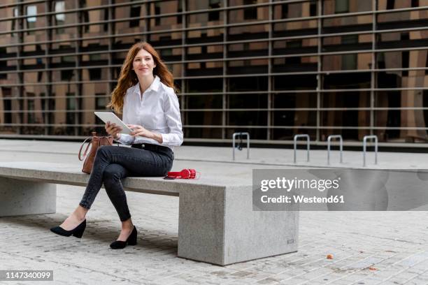 young businesswoman sitting on bench in the city, using digital tablet - sitting bench stock pictures, royalty-free photos & images