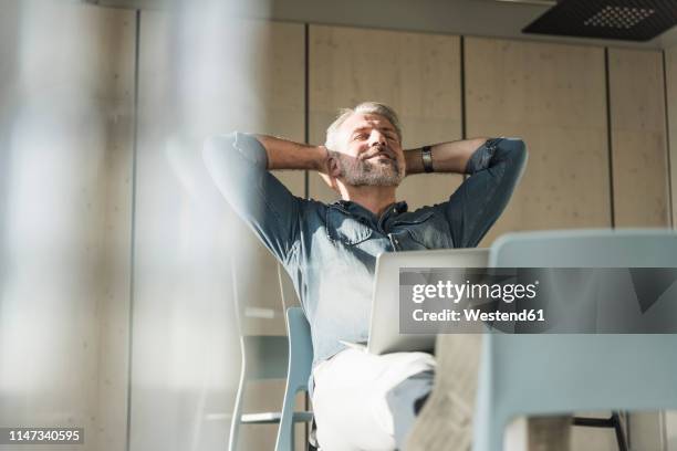 casual mature businessman with laptop leaning back - bending over backwards stock pictures, royalty-free photos & images