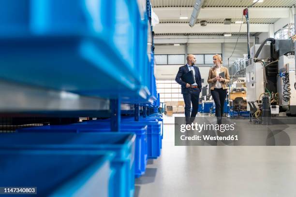 businessman and businesswoman walking and talking in factory - economic discussion stock pictures, royalty-free photos & images