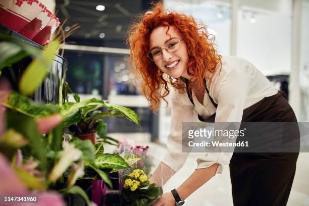 portrait of smiling florist arranging flowers in flower shop - florist arranging stock pictures, royalty-free photos & images