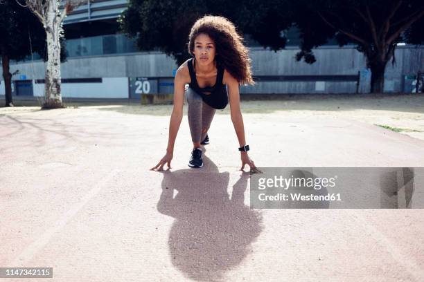 sporty young woman on tartan track starting - sprint stock pictures, royalty-free photos & images