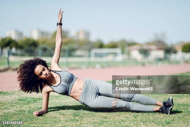 sporty young woman doing side planks on lawn - side plank pose stock pictures, royalty-free photos & images