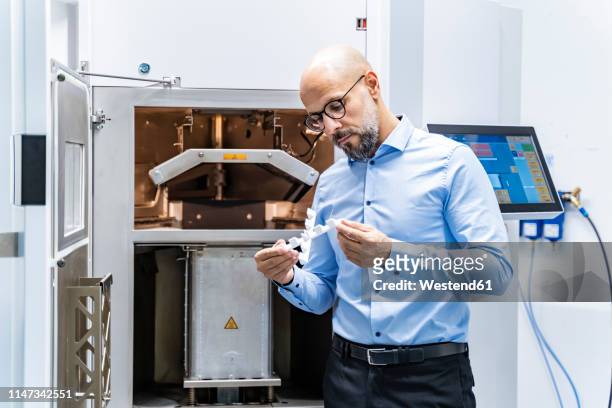man holding workpiece at 3d printer - 3d printing stock-fotos und bilder