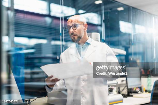 man wearing lab coat holding plan - biomedical engineer stock pictures, royalty-free photos & images