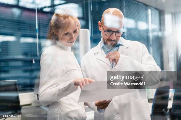 two technicians wearing lab coats looking at plan - la care health plan stock-fotos und bilder