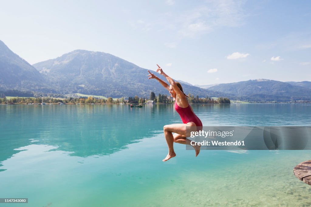Austria, Alps, Salzburg, Salzkammergut, Salzburger Land, Wolfgangsee, woman jumping into lake